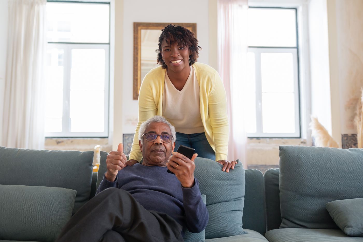 A Black caregiver sharing a warm moment with an older Black man at home
